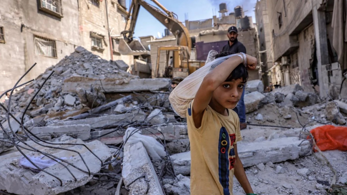 Seorang anak Palestina melihat, ketika para pekerja membersihkan puing-puing sebuah bangunan yang dihancurkan oleh pemboman Israel di Rafah di Jalur Gaza selatan, pada 30 September 2021. Foto: AFP.