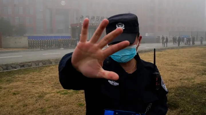 Seorang penjaga keamanan memindahkan wartawan dari Institut Virologi Wuhan. Foto: Foto AP/Ng Han Guan/File.