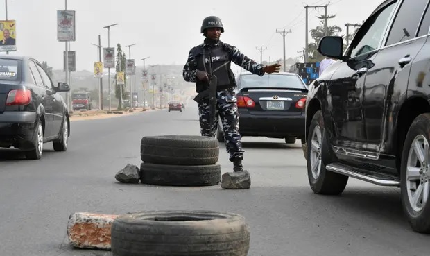 Seorang petugas menghentikan sebuah mobil menjelang pemilihan presiden 25 Februari di negara bagian Anambra, Nigeria. Foto: Pius Utomi Ekpei/AFP/Getty Images
